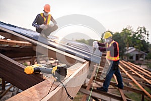 Selective focus Roofing tools, Roofer worker using a  electric drill install on new roof metal sheet at construction site