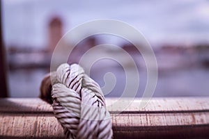Selective focus on a rope rapped and knotted around a metal pole.