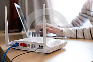 Selective focus at router. Internet router on working table with blurred man connect the cable at the background. Fast and high