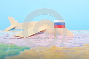 Selective focus of Russian flag in blurry world map and wooden airplane model. Russia as travel and tourism destination concept.