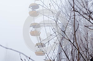 Rust ferris wheel attraction and trees in foggy winter abandoned amusement park in Pripyt, Chernobyl zone of alienation