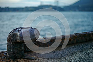 Selective focus of rusted steel post for seizing the ship at the pier photo