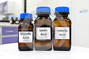 Selective focus of salicylic, lactic and glycolic acid liquid solution in dark brown glass bottle in a white chemistry laboratory.