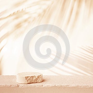 Selective focus.sandstone top product display platform in tropical design with shadow palm leaf on beige pastel wall