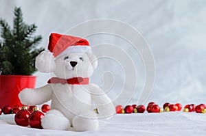 anta claus teddy bear eyes who wearing hat sitting with red baubles and Christmas tree