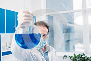 selective focus of scientist with flask in hand