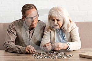 selective focus of senior couple with mental illness matching puzzle pieces.