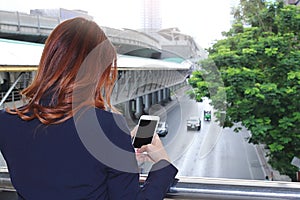 Selective focus and shallow depth of field. Back view of woman taking a photo of traffic car in city with mobile smart phone