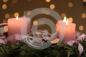 Selective focus shot of an advent wreath decoration with lighted pink candles. perfect for wallpaper