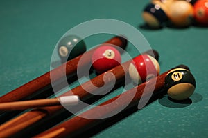 Selective focus shot of billiard balls and sticks on a green table