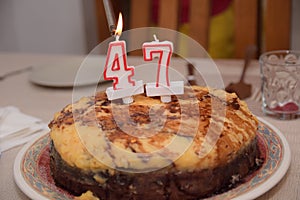 Selective focus shot of a birthday cake with 47 candles burning by lighter