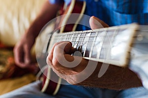 Selective focus shot of an elderly male playing an electric guitar