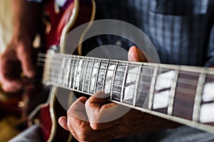 Selective focus shot of an elderly person playing the guitar