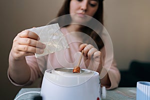 Selective focus shot of female artisan craftperson pouring soy wax into pan to make candles. Process of making handmade