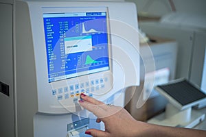 Selective focus shot of a female doctor adjusting the CBC (complete blood count) blood test machine