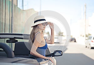 Selective focus shot of female on the driver seat of a white convertible sports car