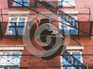 Selective focus shot of a few pairs of shoes hanging to dry outdoors with building in background