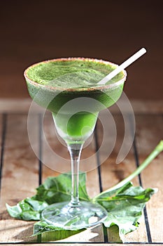 Selective focus shot of a glass of chaya cocktail with a straw on mint leaves