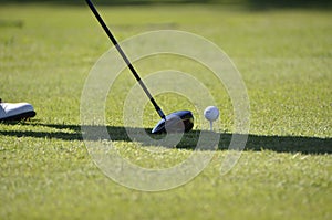 Selective focus shot of green grass with a golf ball and golf club at the sunlight