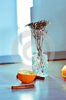 Selective focus shot of half an orange, cinnamons, dry roses, and decorative branches in vases