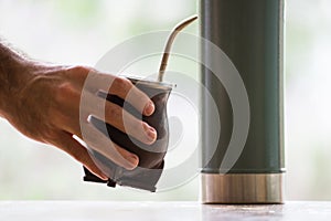 Selective focus shot of a hand holding a  calabash mate cup with straw - yerba mate tea infusion