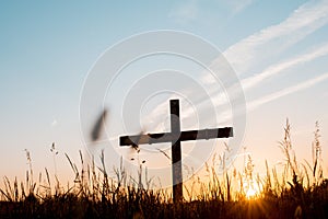 Selective focus shot of a handmade wooden cross in a grassy field under a beautiful sky