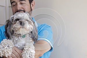 Selective focus shot of a Hispanic man holding a cavapoo puppy