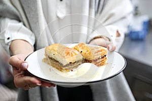 Selective focus shot of a lady holding delicious dessert with vanilla ice-cream in a white plate