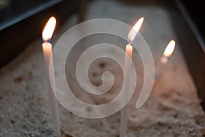 Selective focus shot of lighting candles in a church