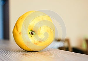 Selective focus shot of a little stale yellow apple on a wooden table