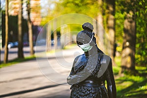 Selective focus shot of a metal female statue wearing a surgical mask