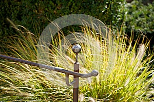 Selective focus shot of a metal handrailing with grass on the background
