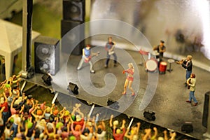 Selective focus shot of a mini toy stage with little figures represented as a band and the crowd