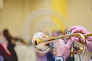 Selective focus shot of a musician playing the trumpet while people are dancing to the music