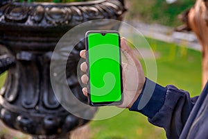 Selective focus shot of a person holding a mobile phone with green blank space for text