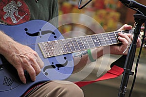 Selective focus shot of a person playing the guitar on the street