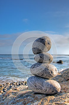 Selective focus shot of piled stones in a seashore with a blurred blue sky in the background