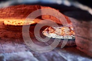 Selective focus shot of a pizza baking in a traditional stone oven