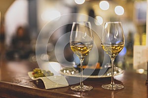 Selective focus shot of plates of shrimp and olives and two wine glasses on a table in a restaurant