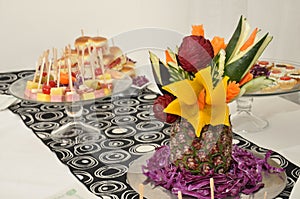 Selective focus shot of a platter of fruit skewers and pineapple art case on a dessert buffet table