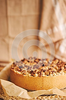 Selective focus shot of a round apple pie topped with crumble and roasted nuts, on a towel