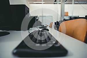 Selective focus shot of row of computers and empty chairs by the desk in the office