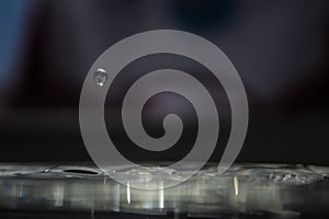 Selective focus shot of a small waterdrop with a dark blurry background