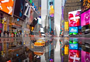 Selective focus shot of a toy vintage taxi car in Times Square of New York