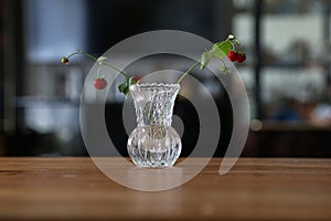 Selective focus shot of twigs with red berries of wild strawberries in a vase