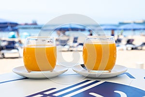 Selective focus shot of two orange juice glasses in white plate on a table