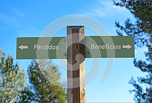 Selective focus shot of a way signpost with Loss and Profit writings in Spanish photo