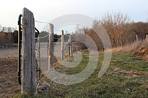Selective focus shot of wooden posts and wire fence on a farm