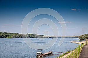 Selective focus on a small boat on the danube river on the serbia croatia river with the ilok backa palanka bridge in background,