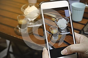 Blogger food with smartphone picture which woman hand holding phone taking photo of stylish flat lay ice cream in the cafe and